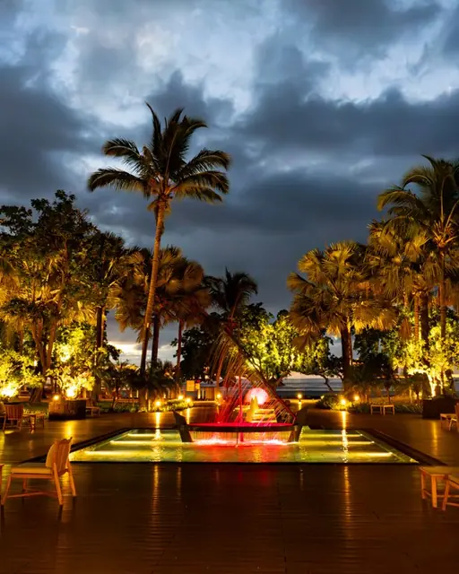 A lit garden and its reflecting pool at nightfall